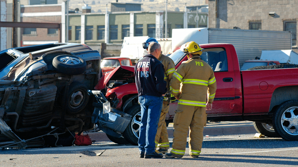 Fireman and bystander standing in front of multi car pileup